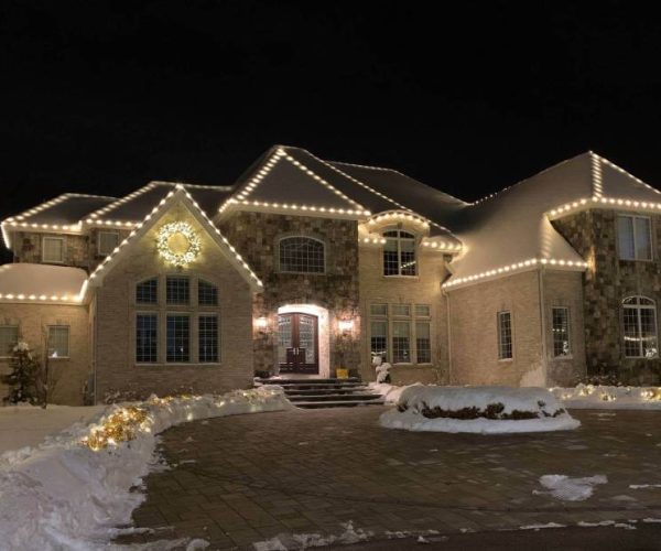 brown brick home with white holiday lights and wreath decoration